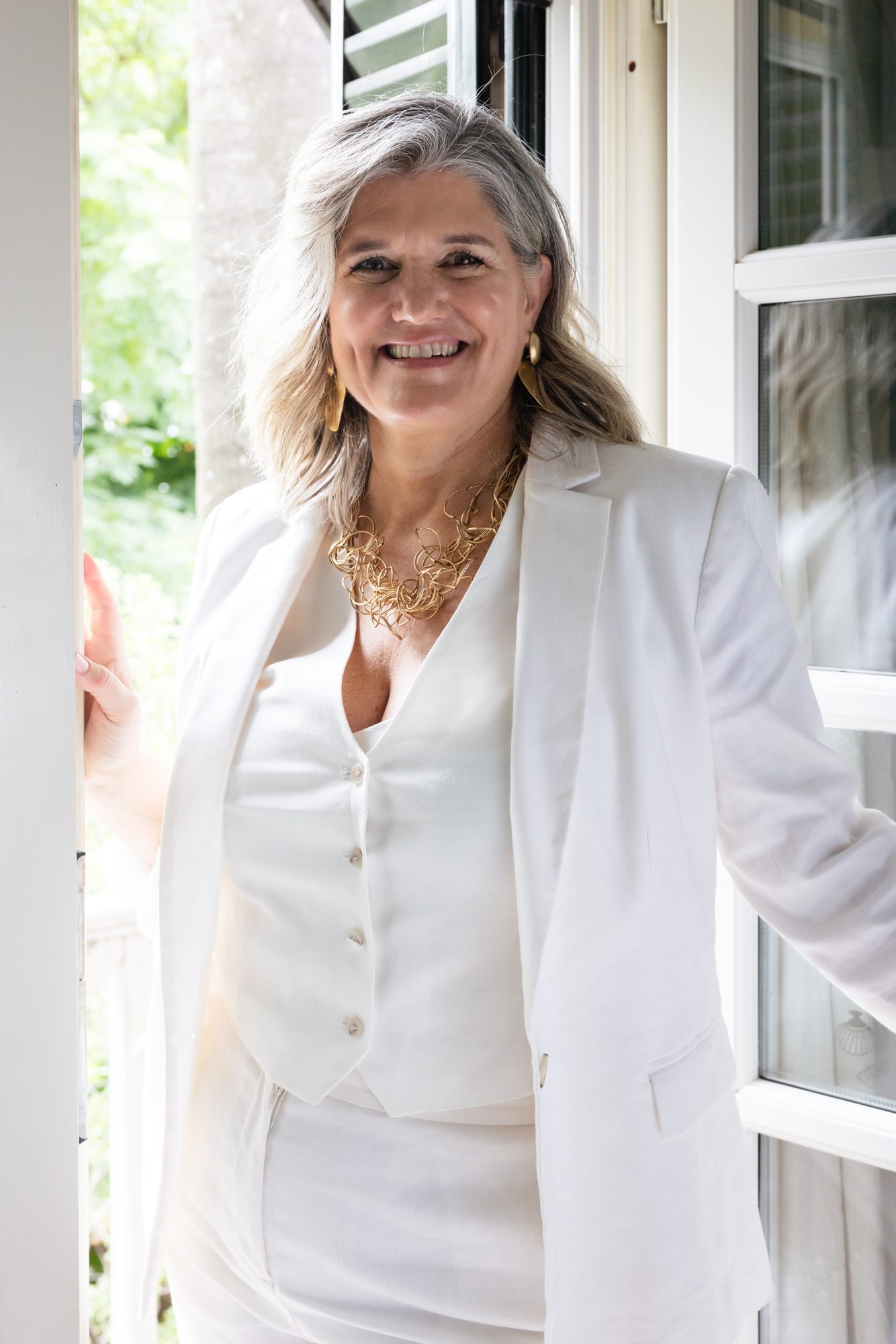 Dolores Hirschmann, founder of Masters in Clarity, laughing in a doorway